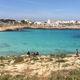 A group of migrants temporarily housed in the shelter, sits by Cala Guitgia, Lampedusa.